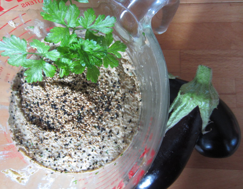 Baba Ghanoush in einer Schüssel, daneben zwei Auberginen